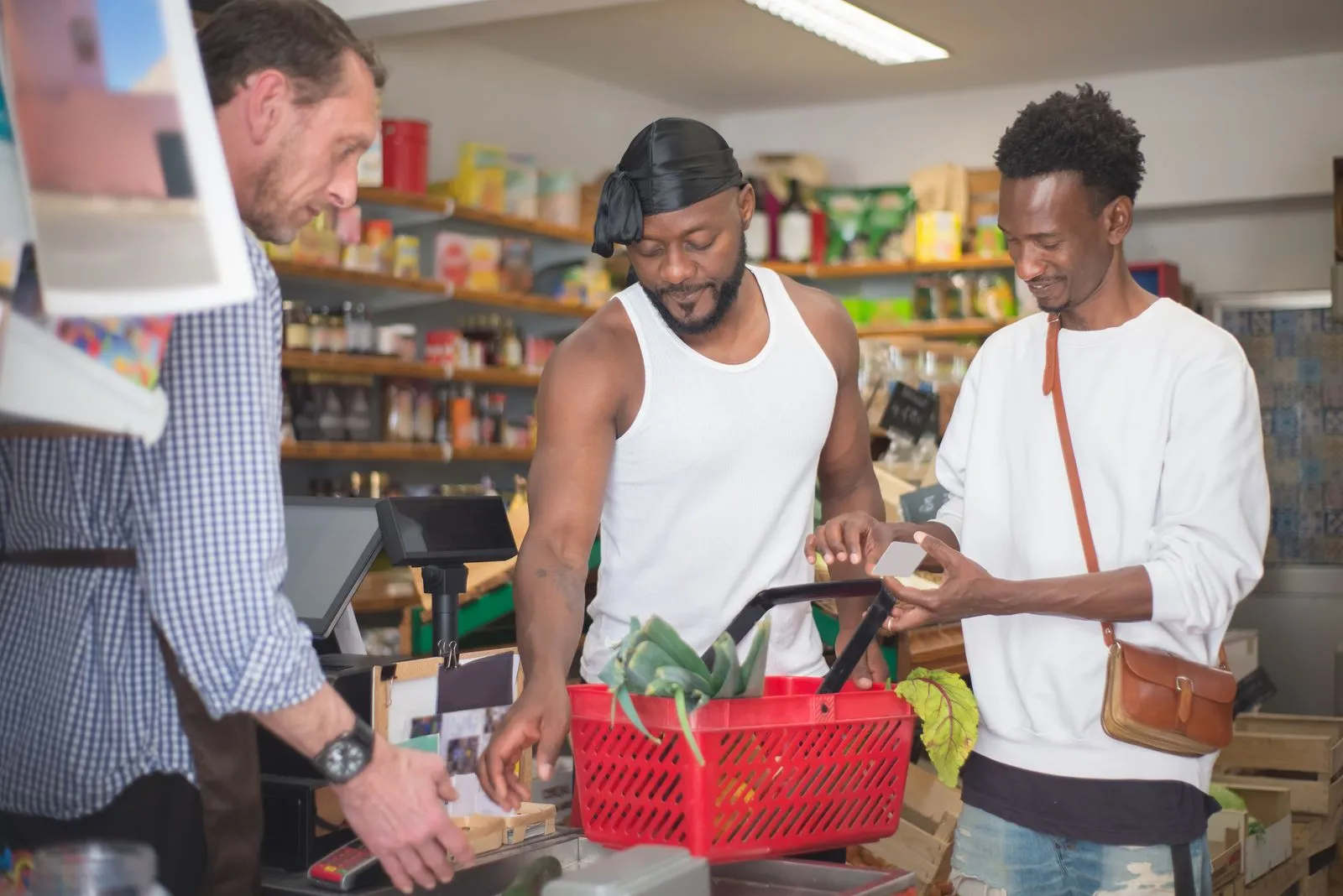 Two friends shopping for groceries in a Portugal store, engaging with a cashier.